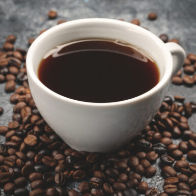 front-view-brown-coffee-seeds-with-cup-coffee-dark-surface